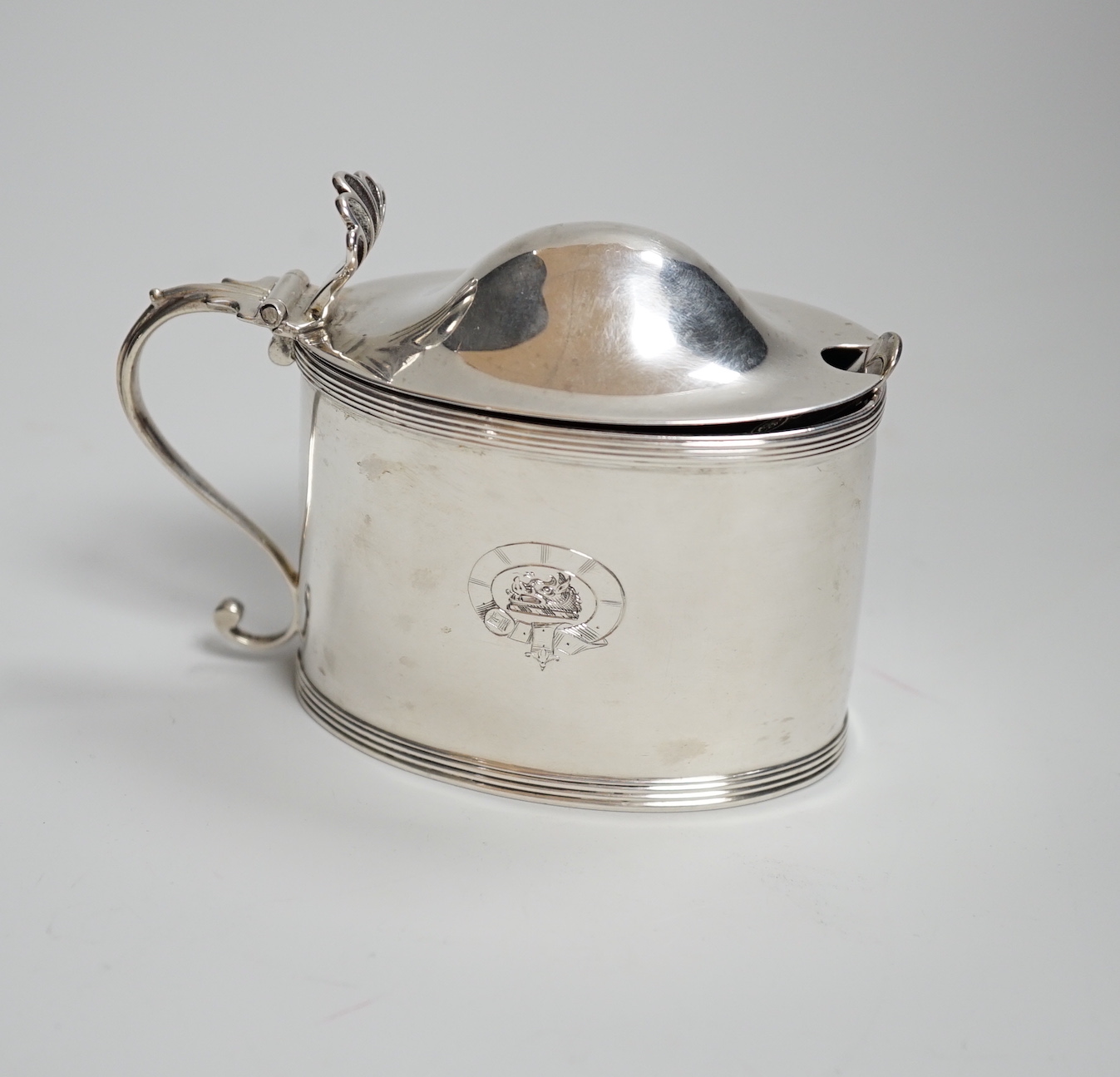 A George III oval silver drum mustard, with domed lid, blue glass liner and associated plated spoon, makers Peter, Anne and William Bateman, London 1799, 110 grams